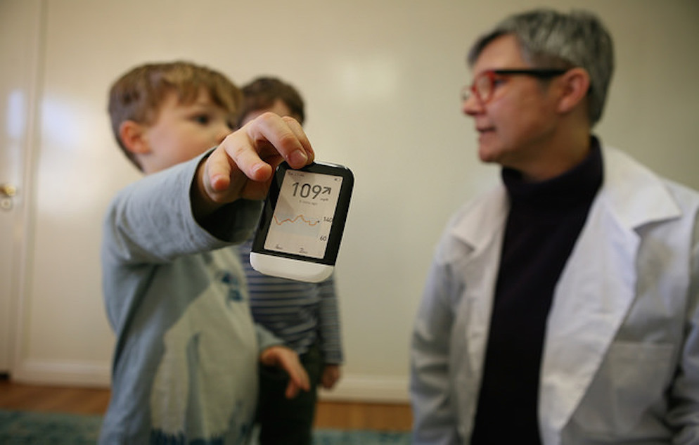 Doctor sitting next to a child holding a diabetes reader