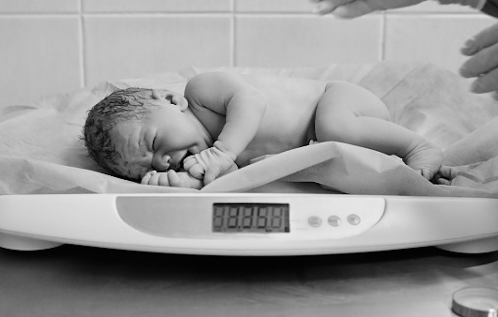 Image of a baby laying on its side on a scale.