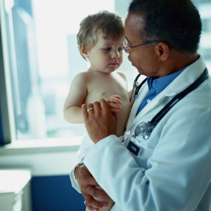 African American doctor holding a Caucasian toddler boy (18-21 months)