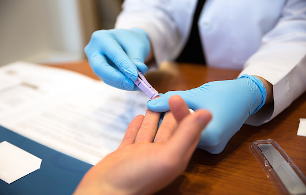 Patient getting a blood test from a doctor on the ring finger of their right hand
