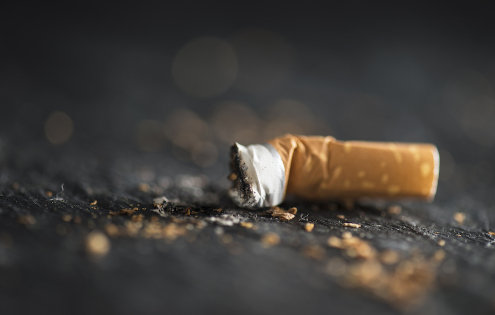 Cigarette butt on dark abstract background.