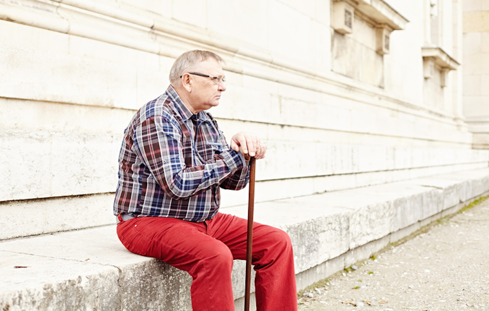Portrait of mature man in glasses and plaid shirt resting leaning on his wooden walking stick
