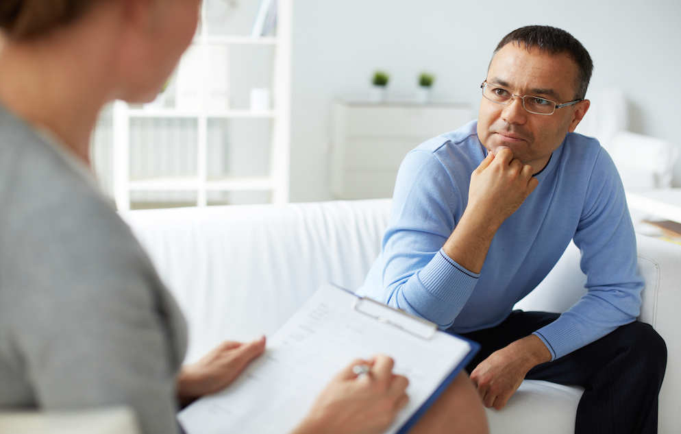 Pensive man in eyeglasses listening to psychologist