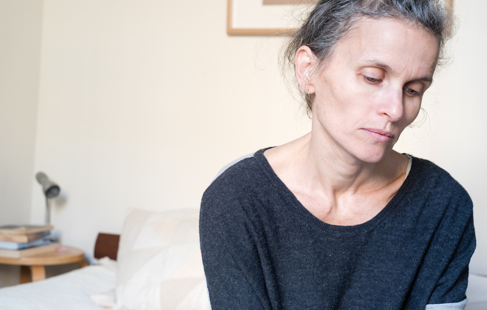 Middle aged woman in bedroom looking sad and depressed