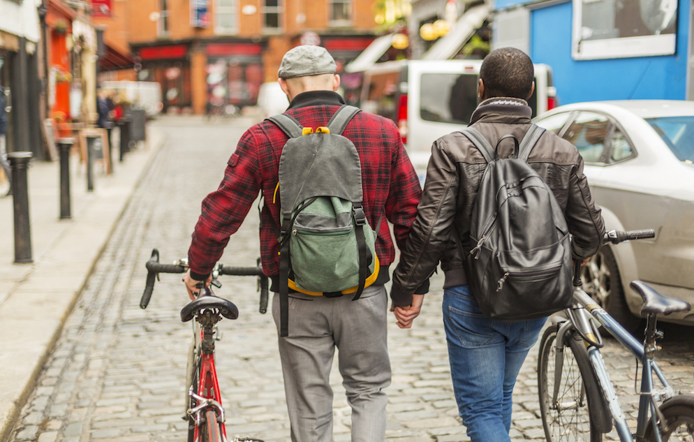 Mixed race gay men with bicycles in a city