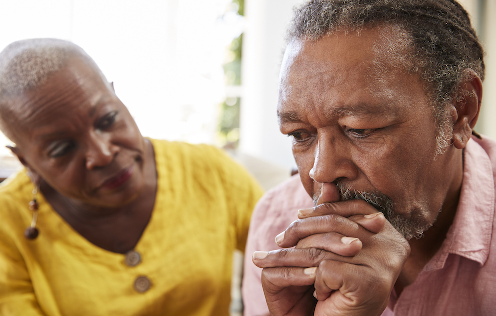 Elderly man looking pensive while elderly woman looks on