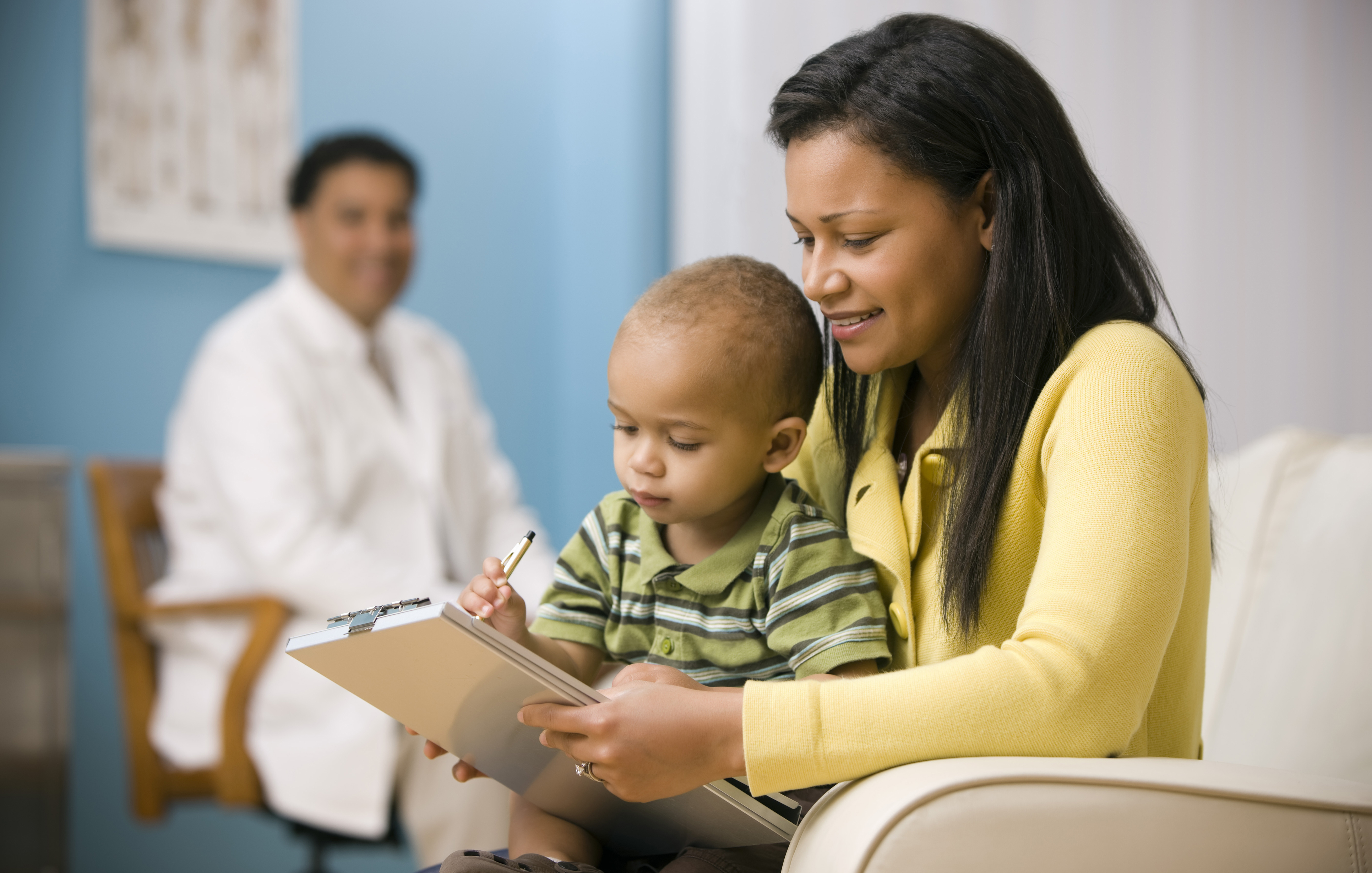 Mother and baby son filling out form in waiting room