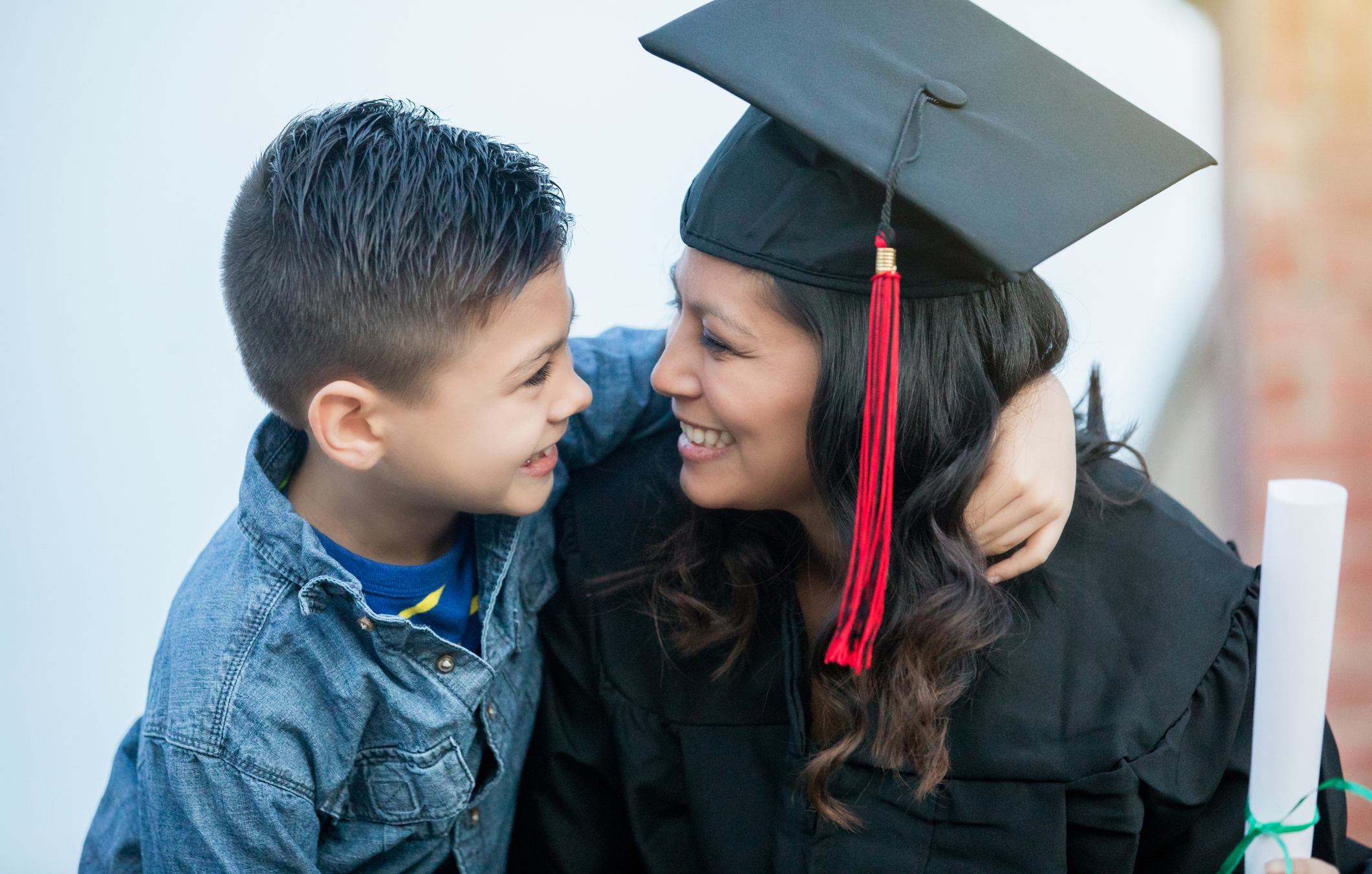 Woman wearing graduation cap and gown sitting with a child