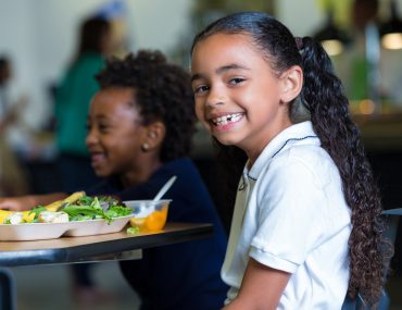 Elementary school girls eating healthy lunch in school cafeteria