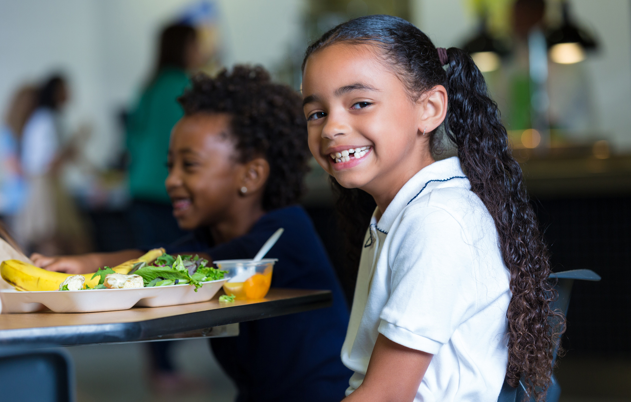 Elementary school girls eating healthy lunch in school cafeteria