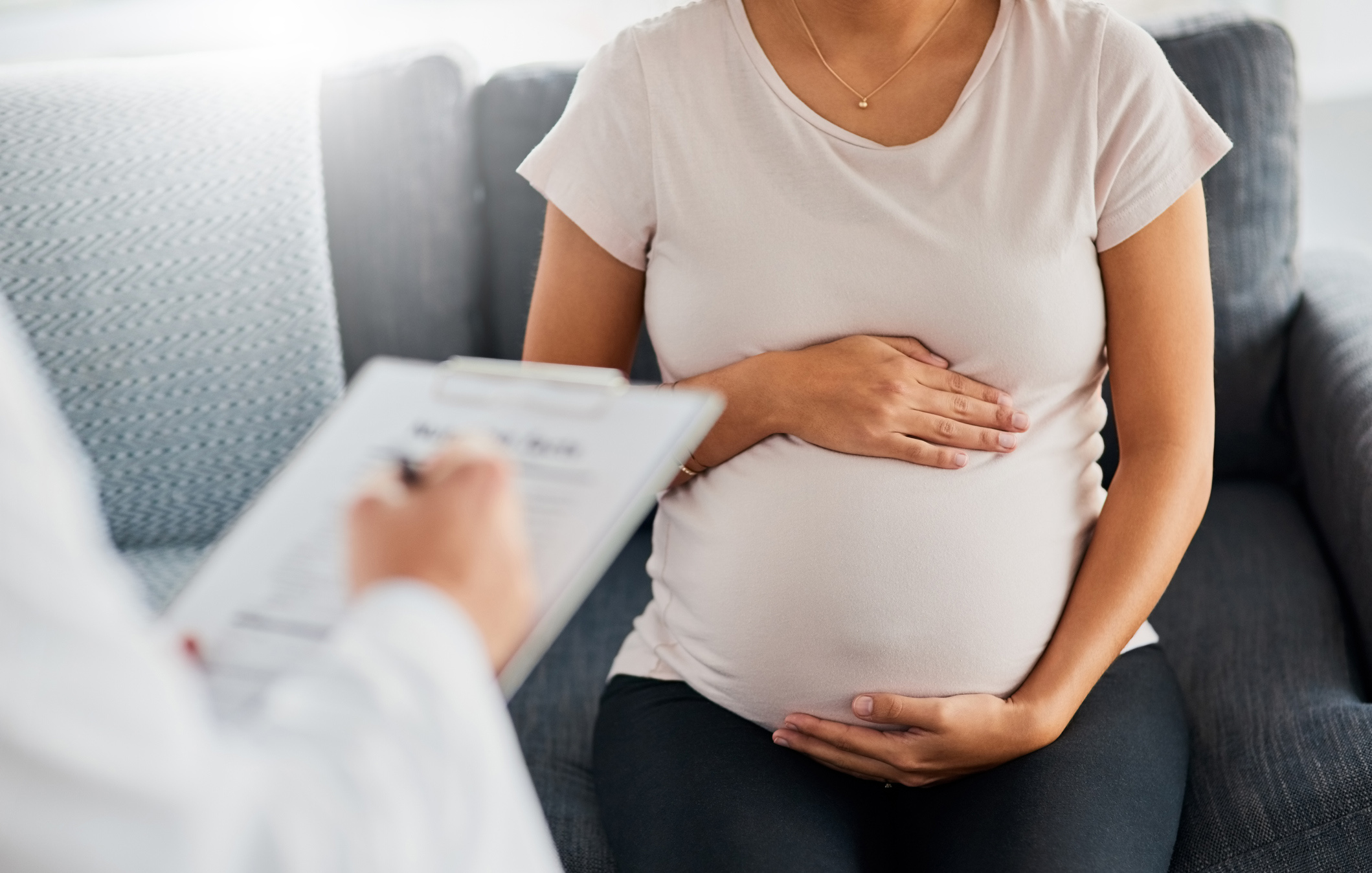 pregnant woman speaks with doctor with clipboard