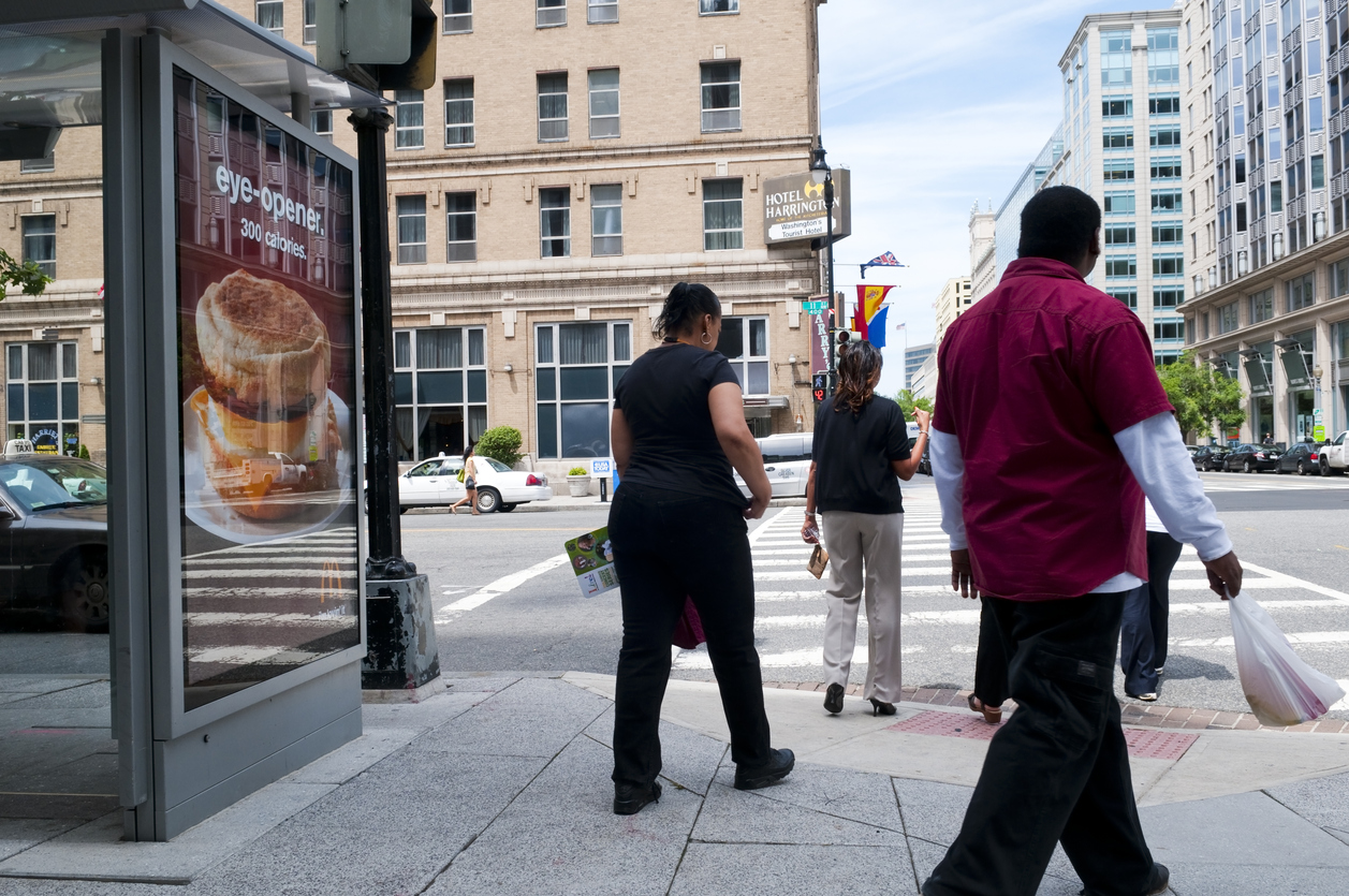 Pedestrians walk past a bus stop with a McDonald's advertisement.