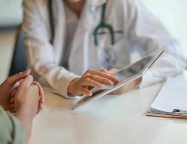 doctor showing a patient some information on a digital tablet