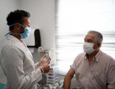 Doctor explains vaccine to older man