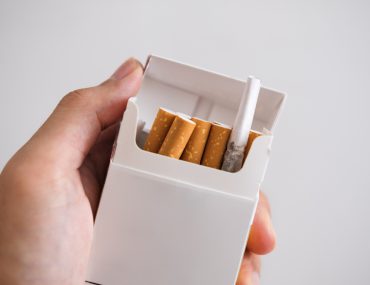 Hand holding cigarette box with hiding Marijuana rolled joint inside