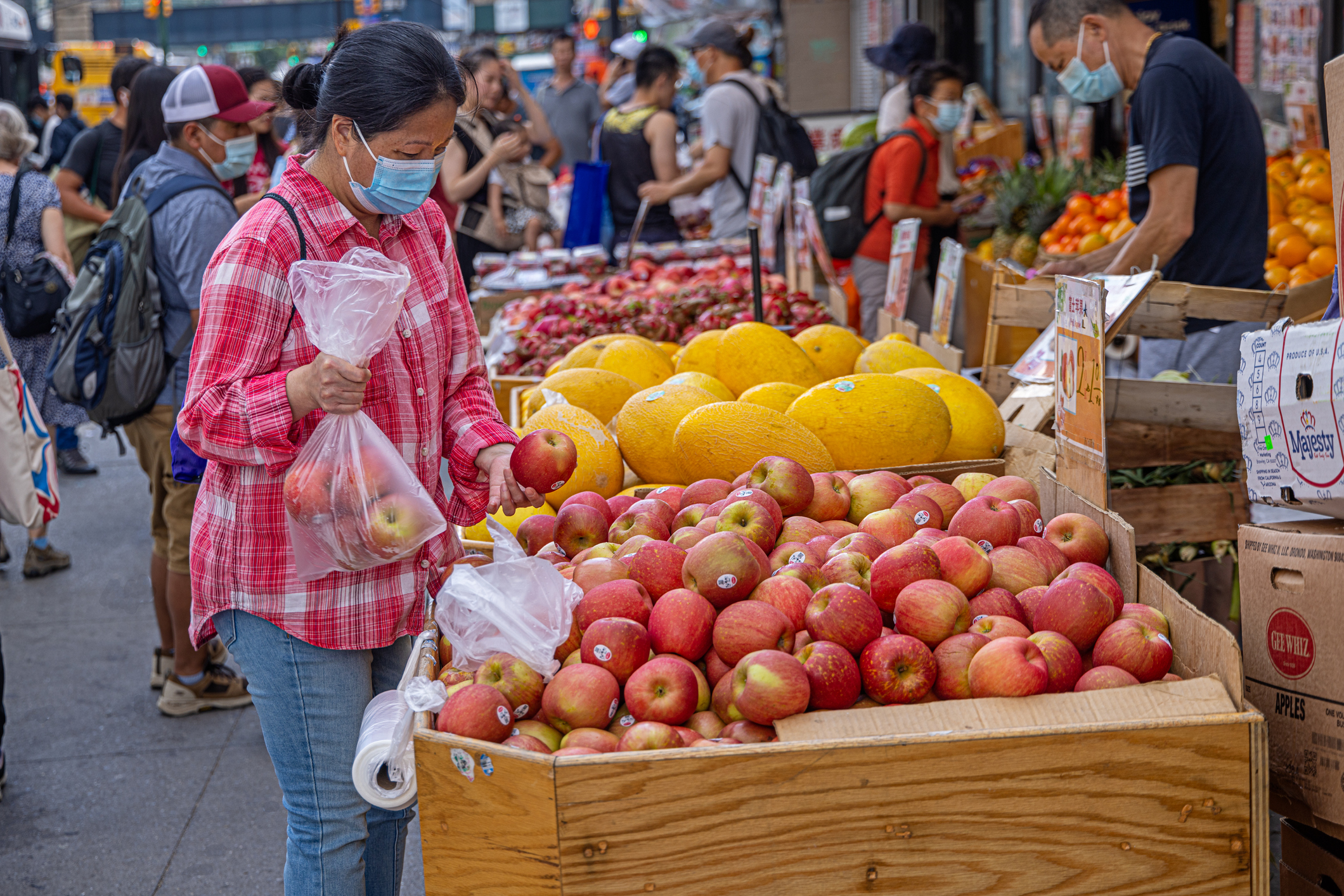 Woman with a facemask buying fruits at a street market