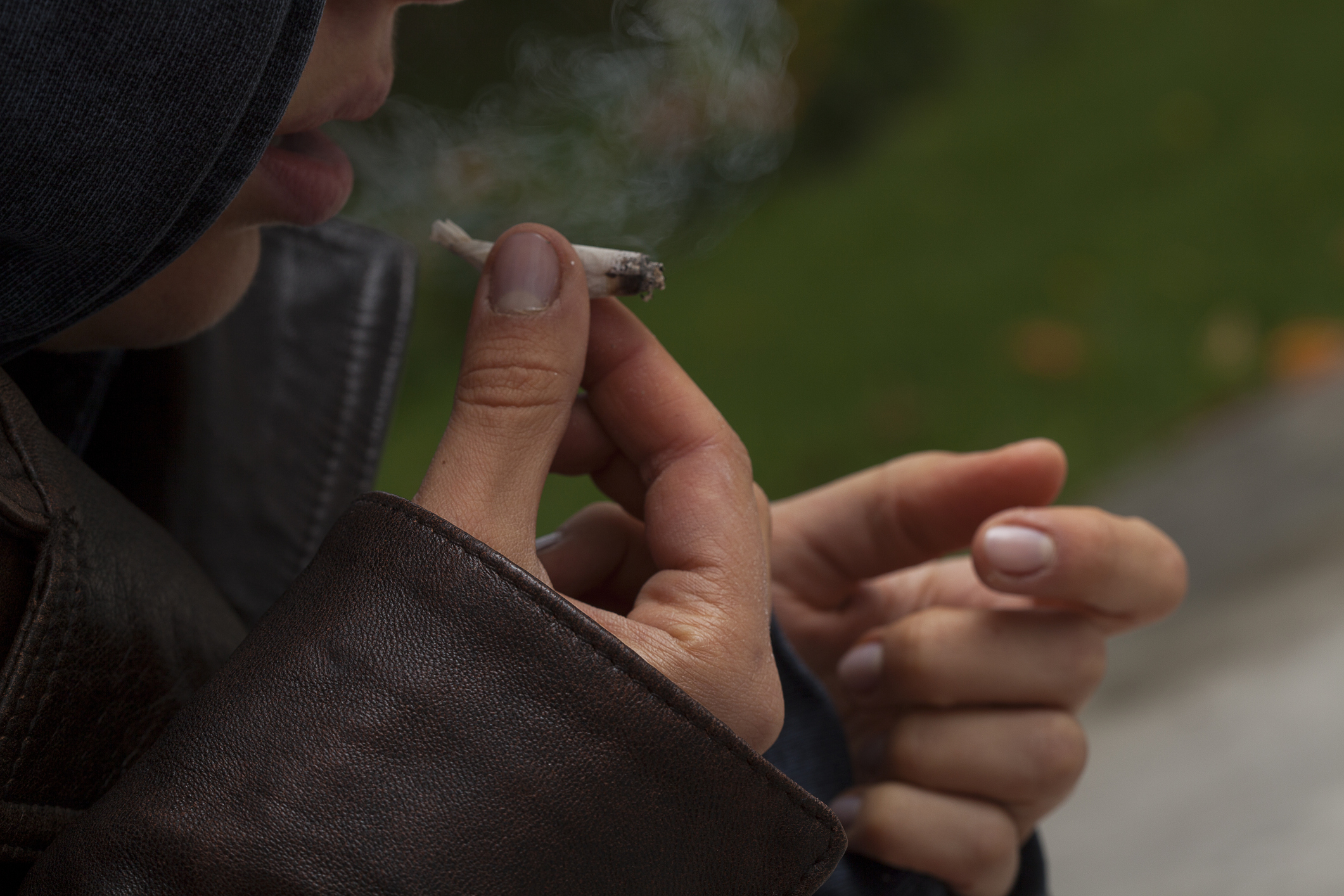 Young girl wearing leather jacket smoking a joint