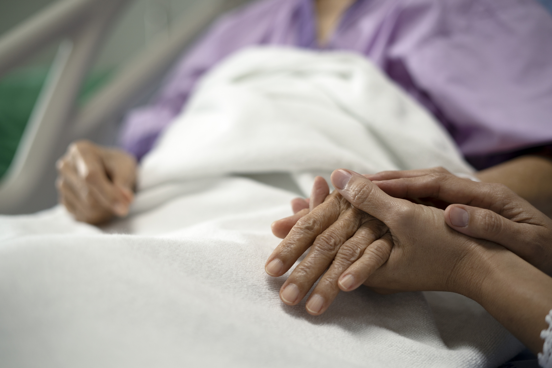 hands holding hospital patient's hand