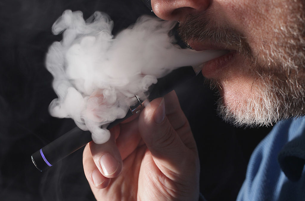 man with gray beard uses e-cigarette