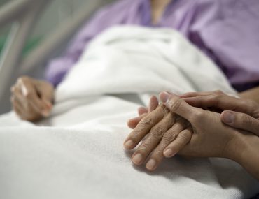 person holding hand of patient in hospital