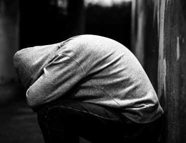 Homeless man alone in cold dark subway tunnel in the city