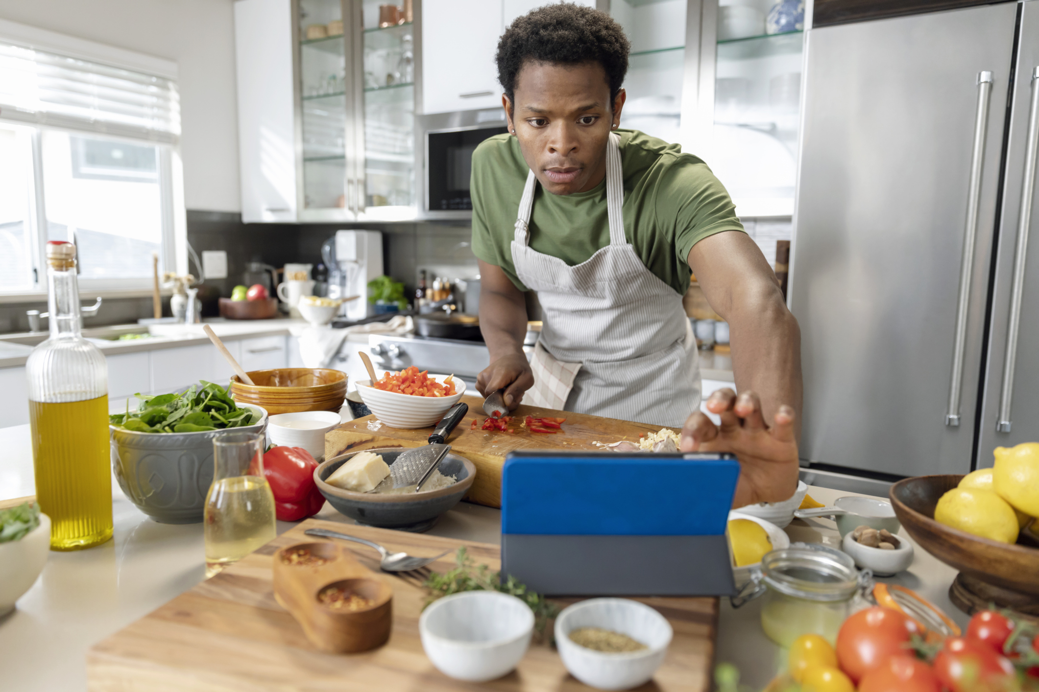 Young man preparing healthy meal with online recipe in kitchen