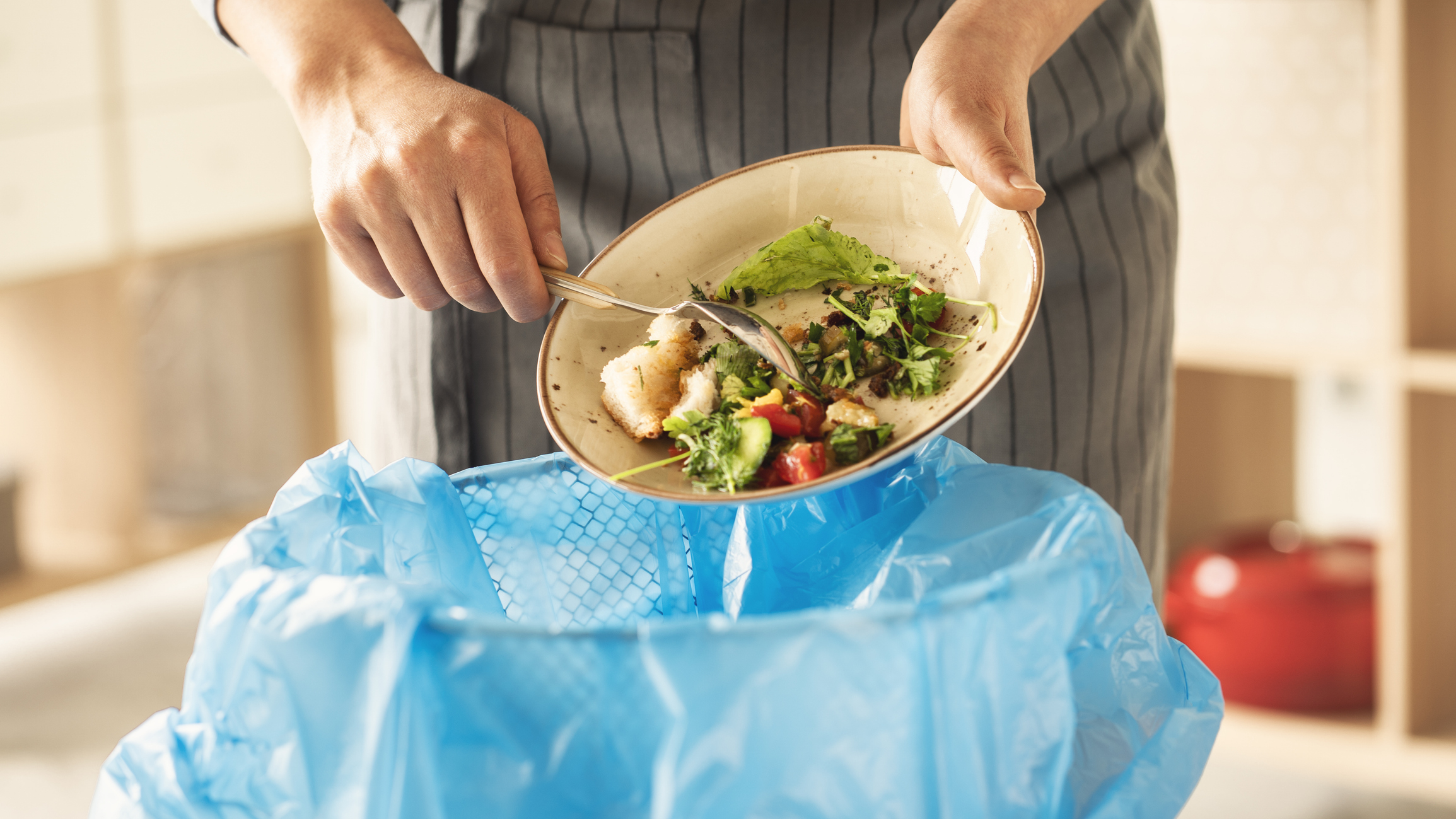 person scraping a plate of food into the trash