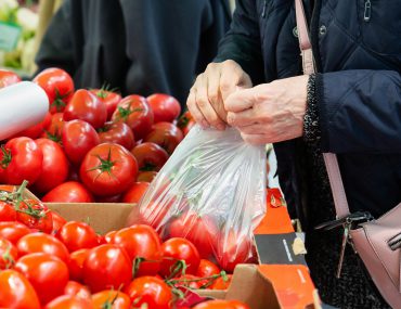 Selecting and buying fresh tomatoes at a farmers' vegetable market.