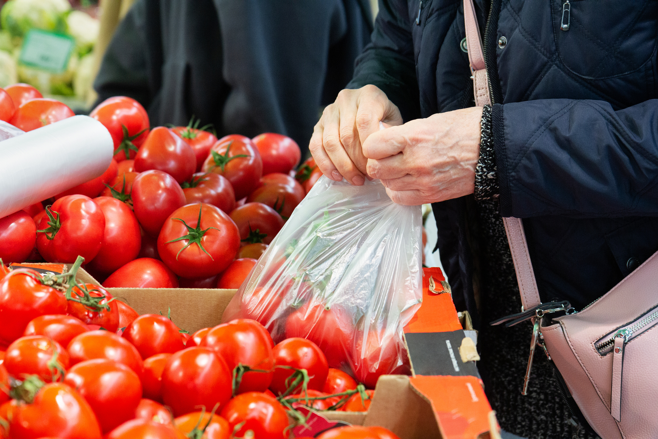 Selecting and buying fresh tomatoes at a farmers' vegetable market.