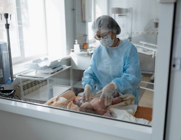 doctor in PPE examines newborn