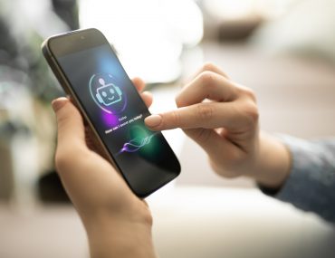 Unrecognisable female hand is using AI chat bot on smart phone.