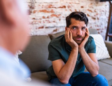 young man looks uncomfortable as he listens to therapist