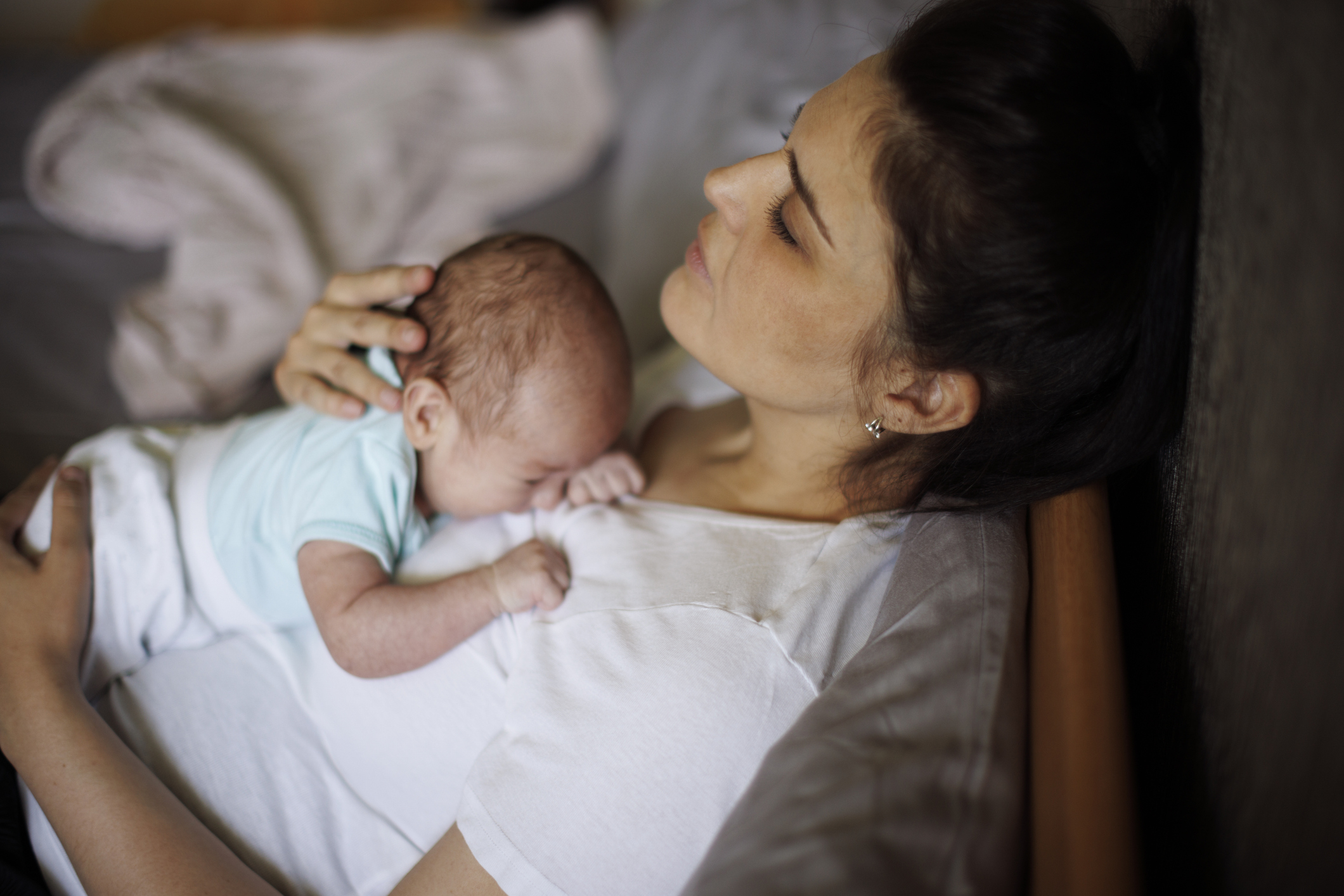 Exhausted mother holding her crying newborn baby