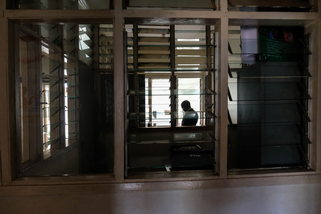 Kampala HIV clinic director is pictured through a window of the organization's empty facilities.