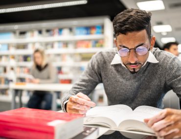 Young man reading a book at library