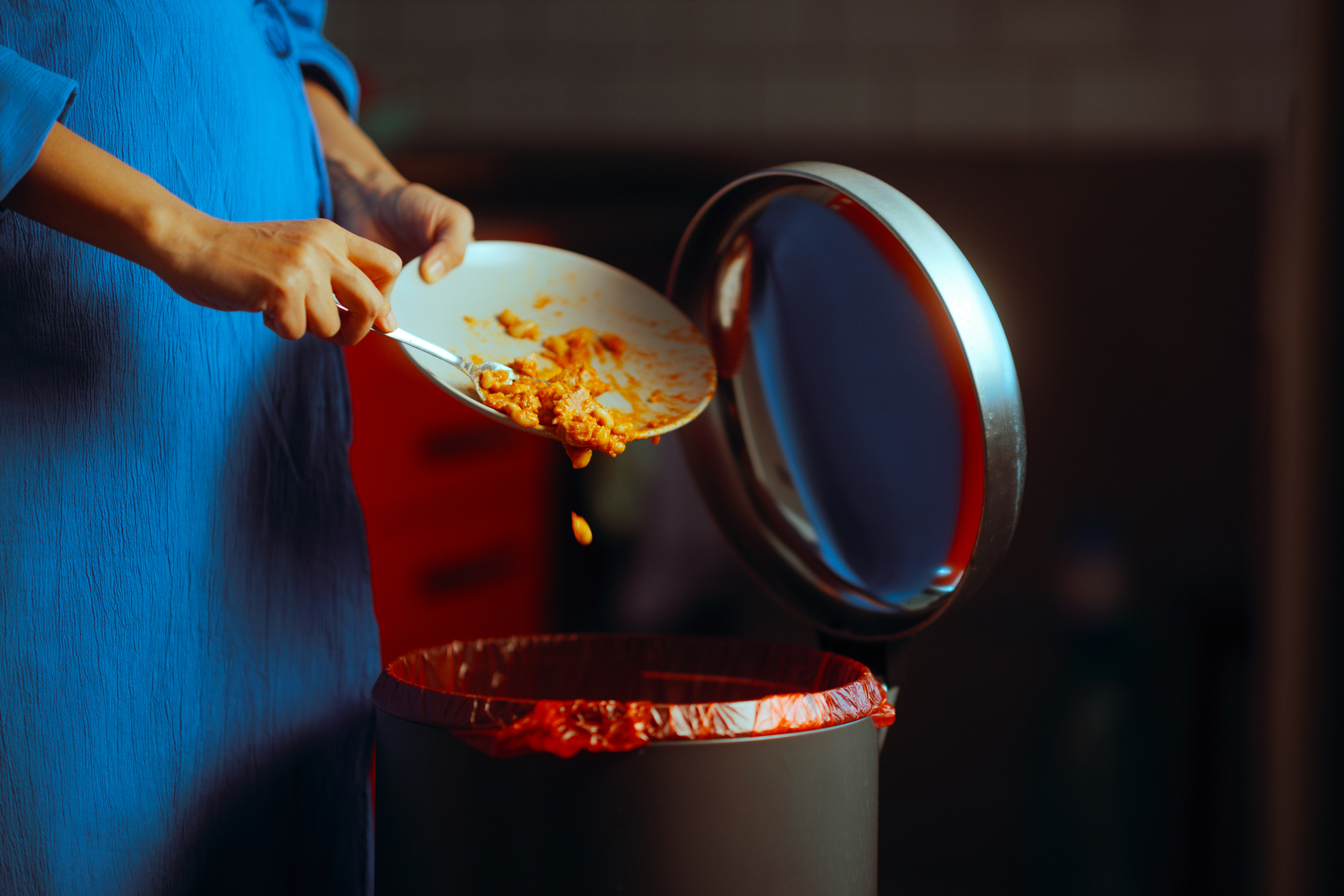Person scraping food into trash can