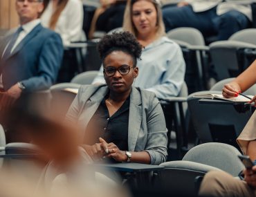 Black woman listens to instructor in lecture hall