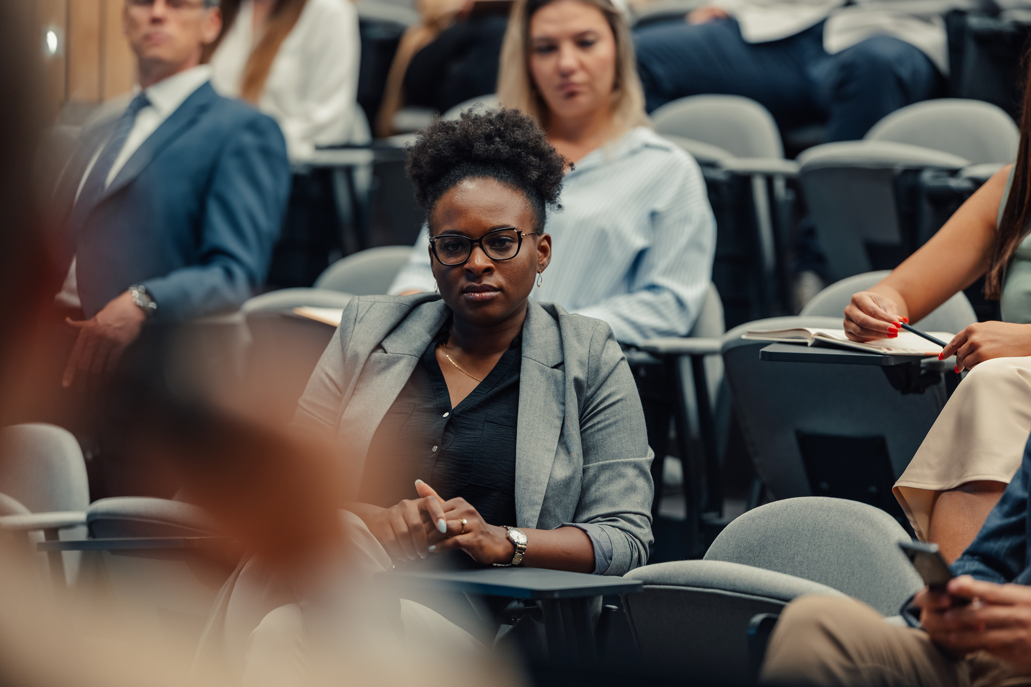 Black woman listens to instructor in lecture hall